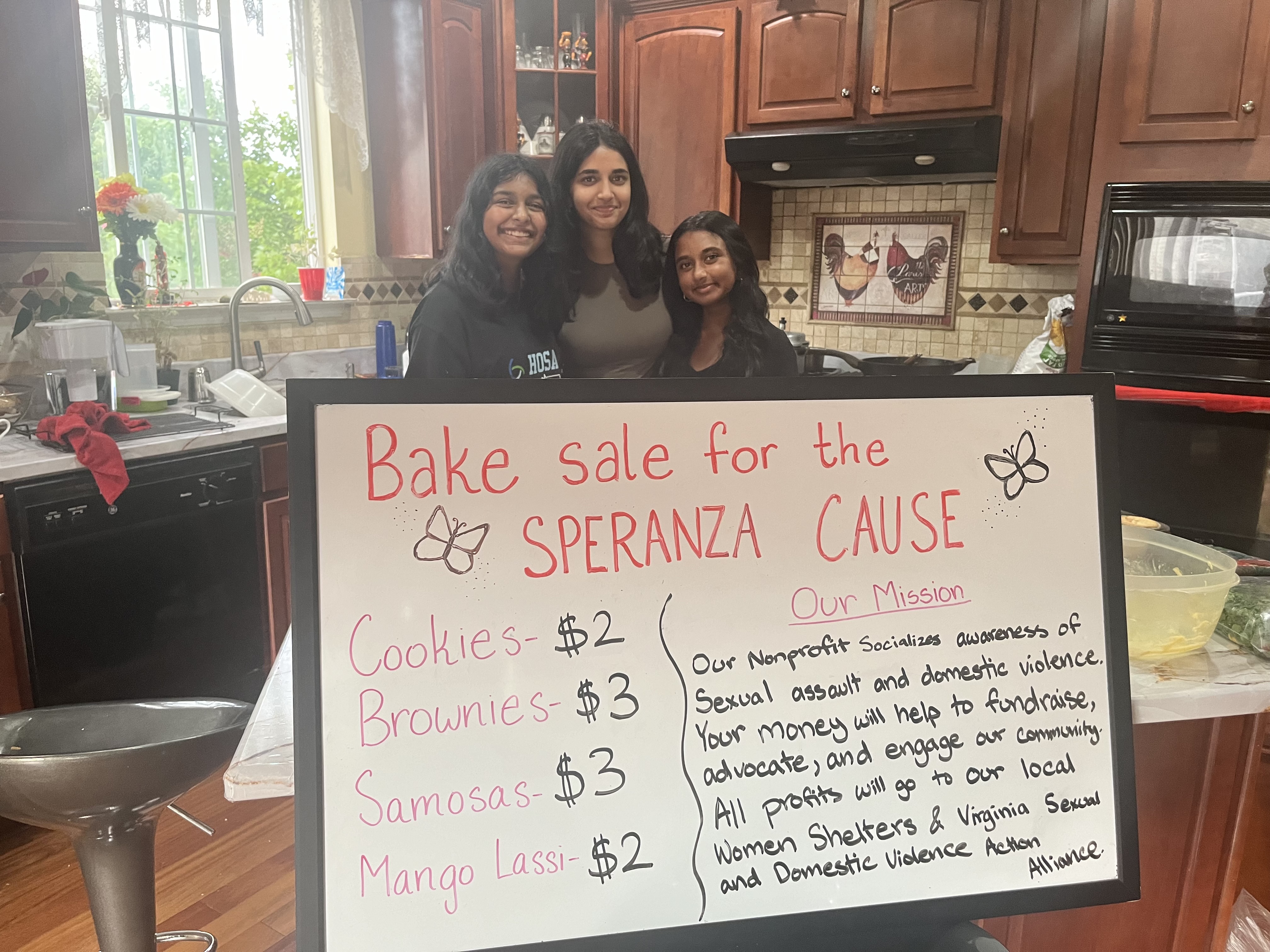 Students standing behind a sign for a Speranza Cause bake sale fundraiser.