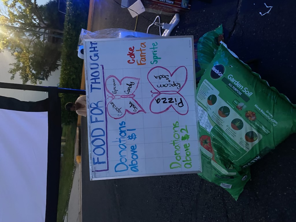 A fundraiser sign showing snacks and donation amounts at an outdoor movie night.